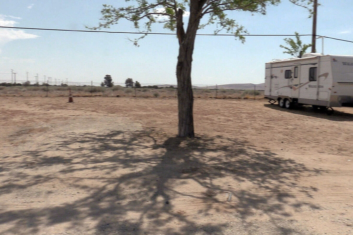 Dirt lot for overnight RV's with an white RV parked on lot.