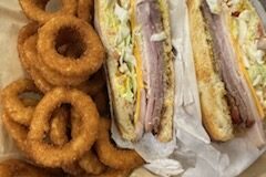 Turkey and ham sandwich with onion rings.