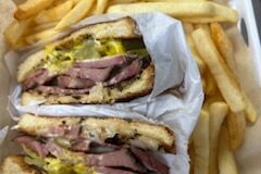 Mean sandwich with pickles and fries.